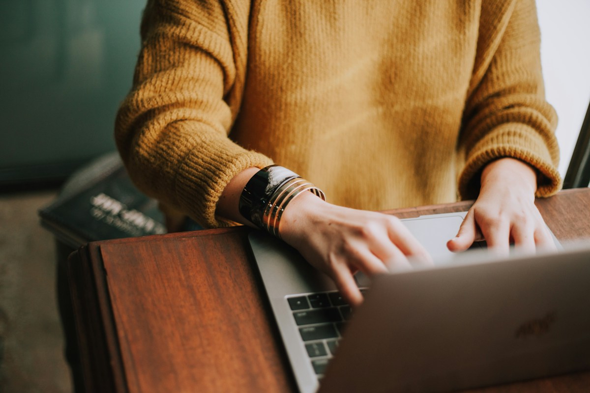 Person working on a laptop at a wooden desk